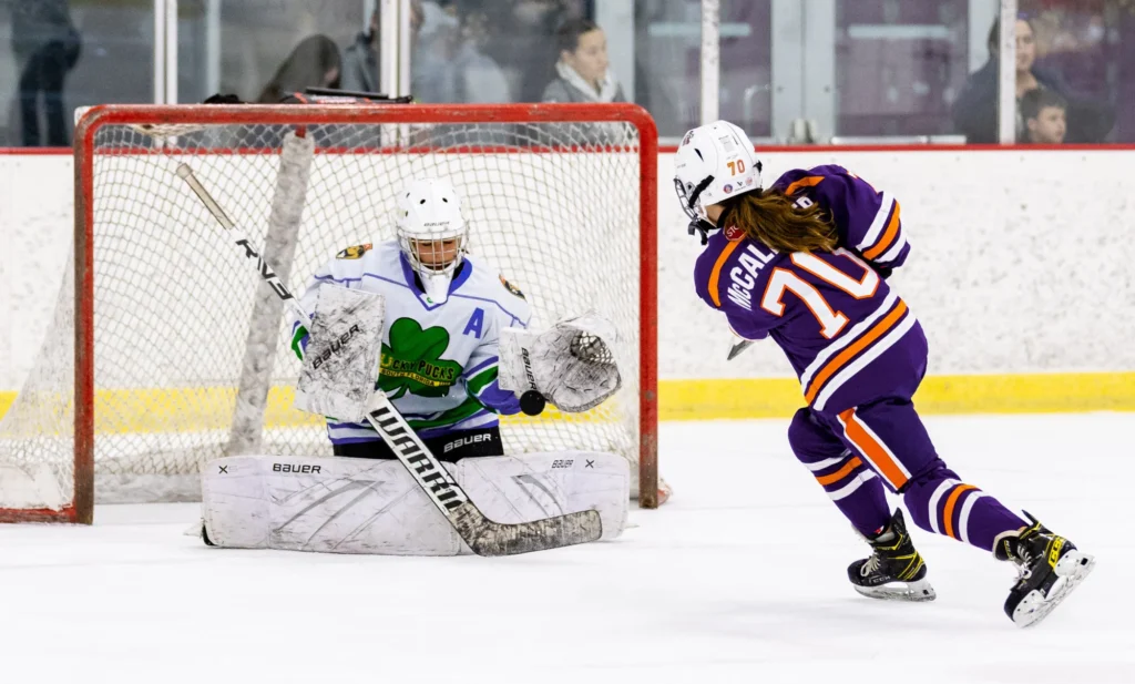 A skater in a purple and orange jersey moves in on a goalie during the breakaway event at the SGHL All-Star Skills Competition.